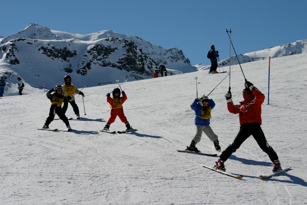 Instructor leading ski lesson of four kids