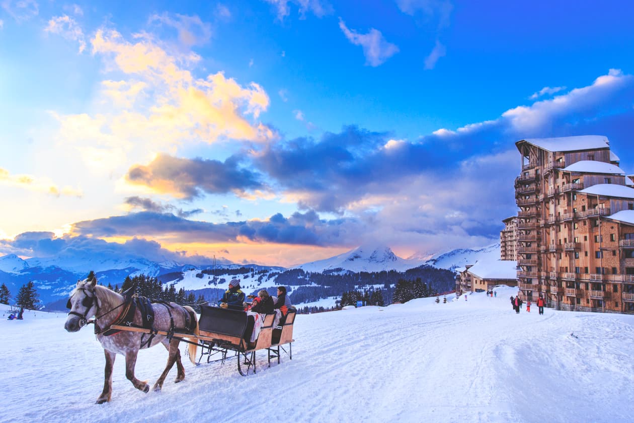 Family taking ride on Horse drawn cart through snowy ski resort Avoriaz