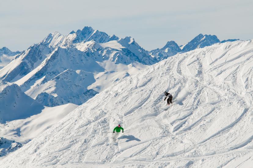 Skiers carving down off piste slope in 4 Vallees