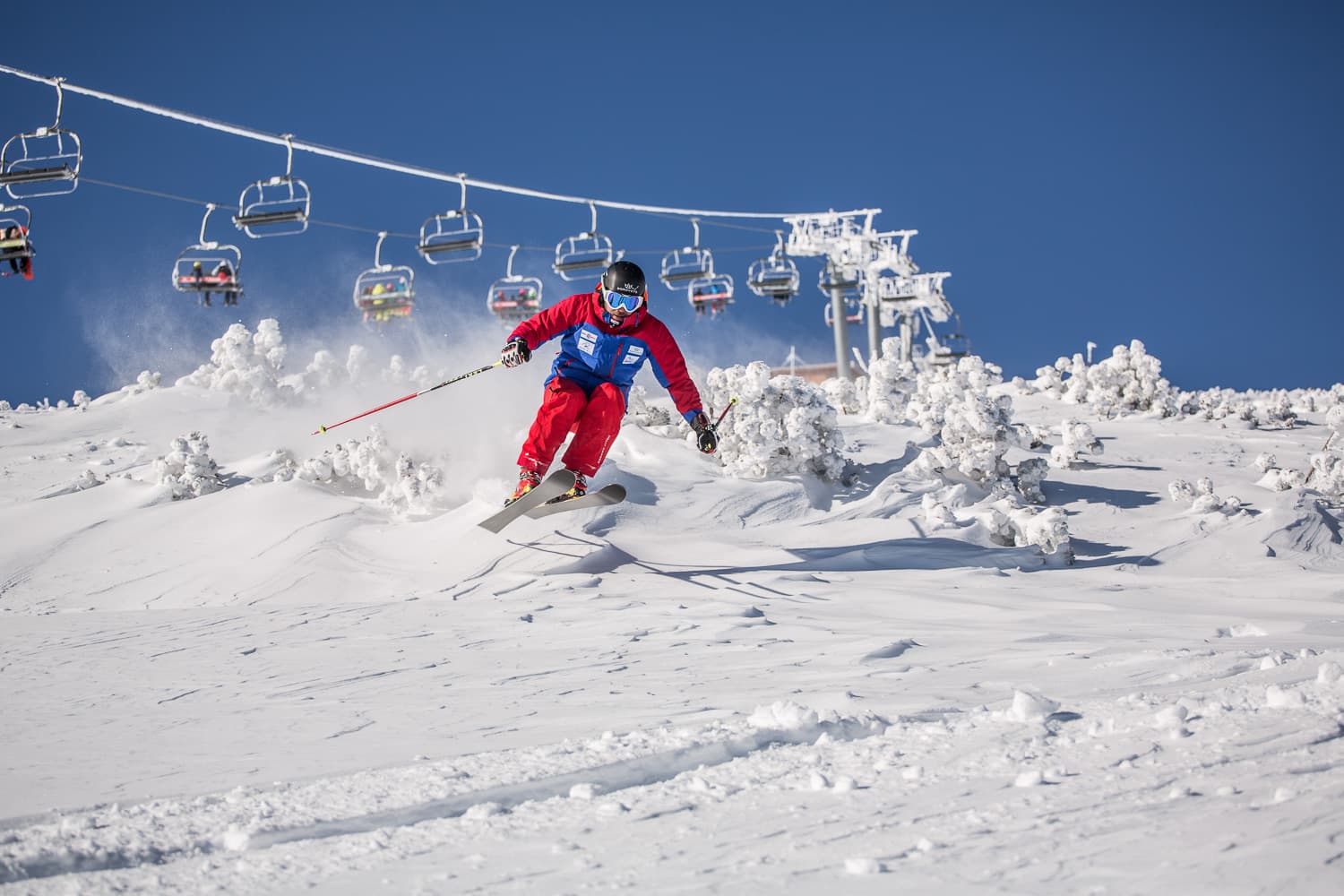 off-piste skier in front of chairlift surrounded by snow-covered trees