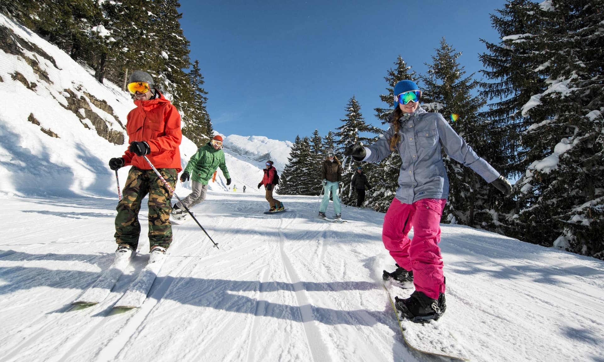 Group of friends skiing down tree lined slope in La Clusaz