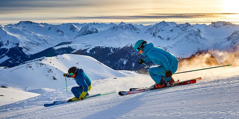 skiers carving at sunset