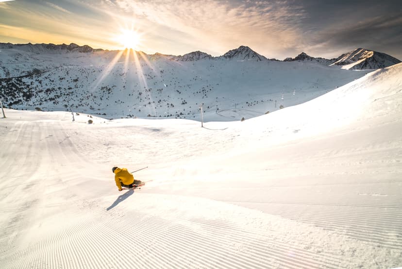 Skier in yellow jacket carving down ski slope in Soldeu ski resort