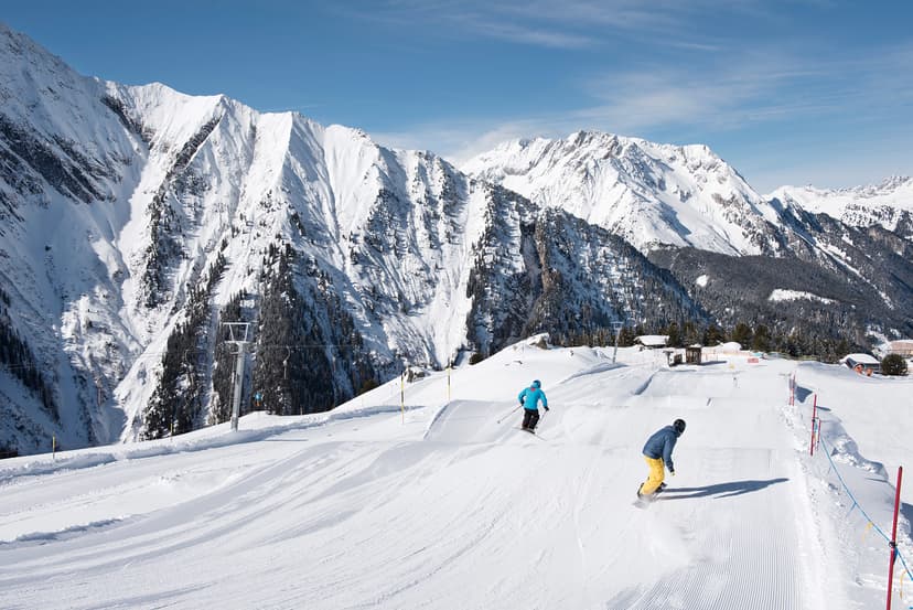 snowboarders riding snowpark jumps in Austrian ski resort