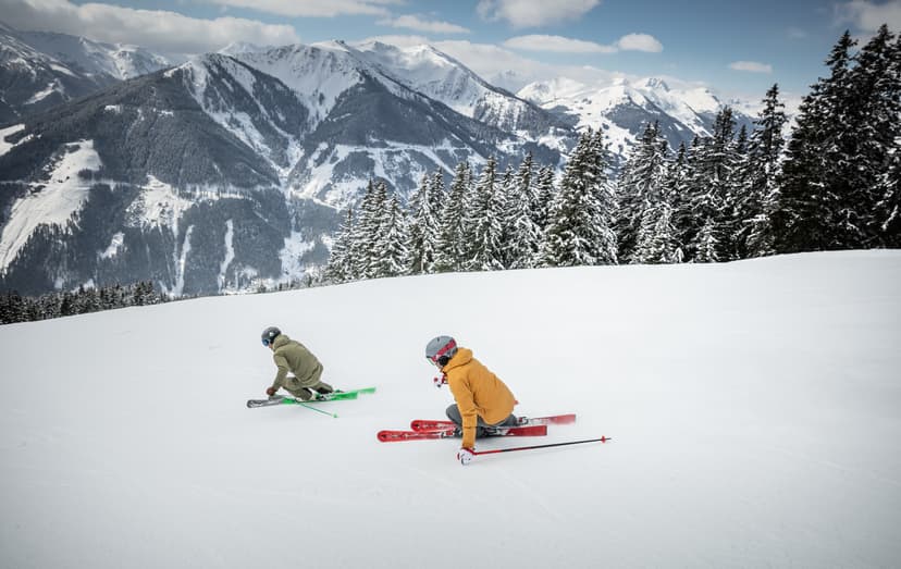 Skiiers skiing down tree lined ski slope in saalbach ski resort