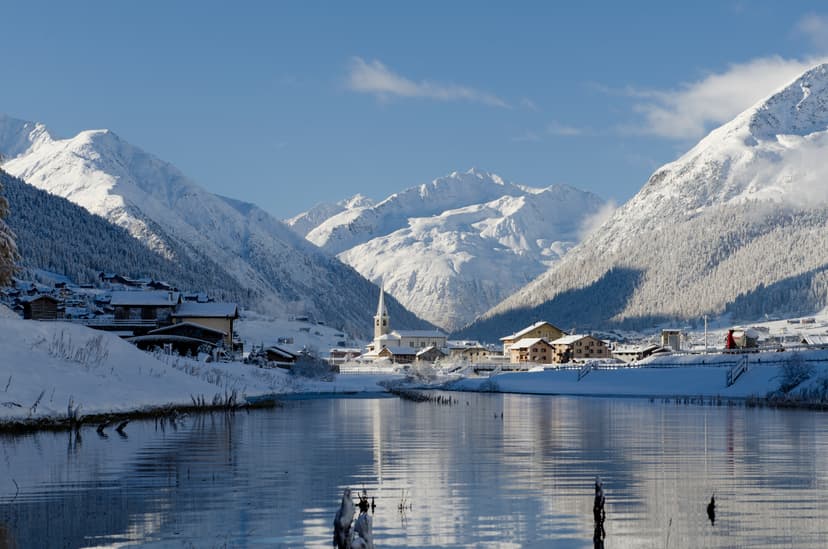 Snowy scenic landscape of Livigno with lake in foreground and mountains in background